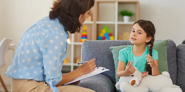 young girl in speech therapy session with therapist