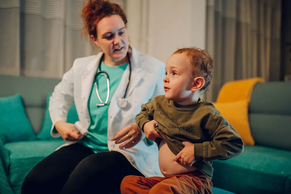 young boy putting on shirt with help of doctor