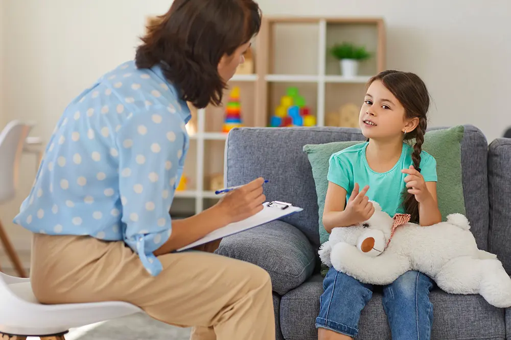 young girl in speech therapy session with therapist